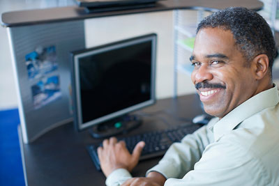 A man smiling next to a laptop