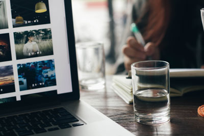 A cup of water next to a laptop