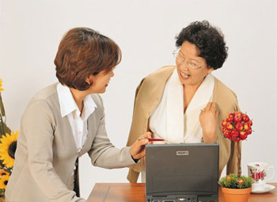 Two people talking in an office while looking at a laptop