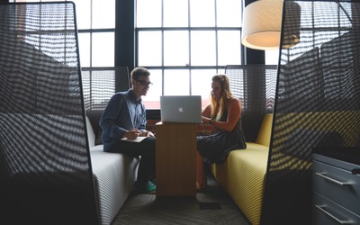 Two people talking near a laptop