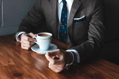 A person in a suit drinking coffee